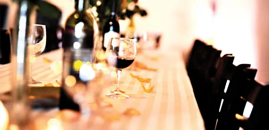 Table set with wine bottles, red wine glass, and decorative petals.