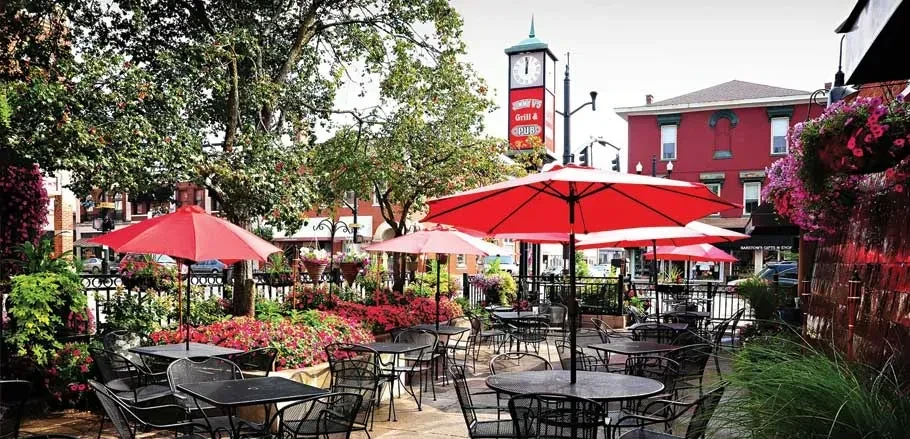 Outdoor patio with red umbrellas, flowers, and "Tommy P's Grill & Pub" sign.