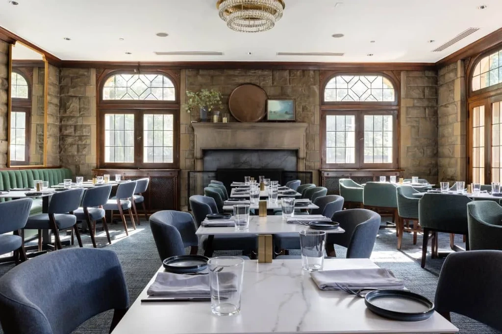 Rustic-elegant restaurant dining room with stone walls and crystal chandelier.