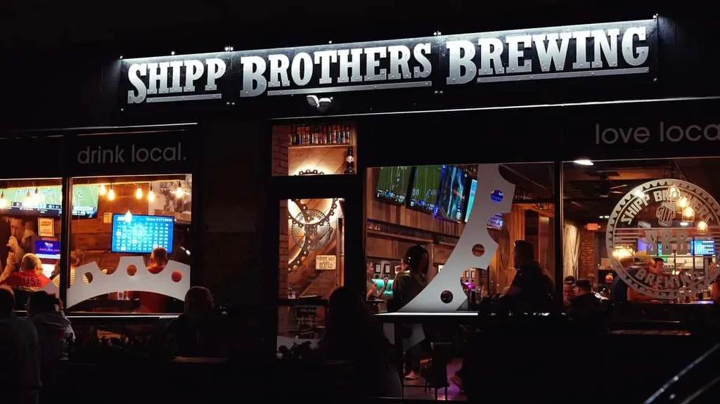 Shipp Brothers Brewing exterior at night, lively industrial-style bar inside.