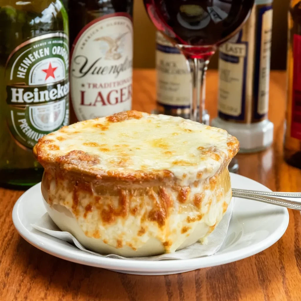 Close-up steaming French onion soup with melted Gruyère on a wooden table.