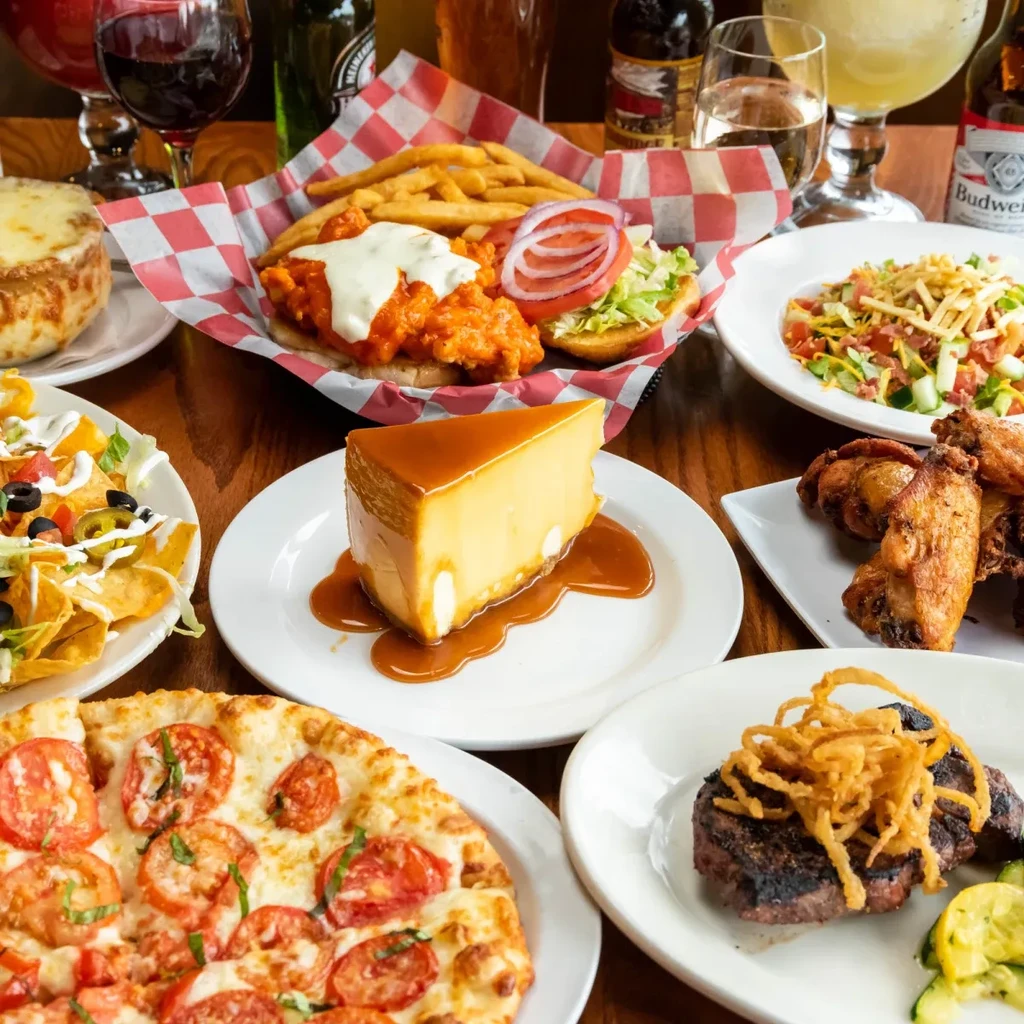 Spread of diverse restaurant food and drinks on a wooden table.