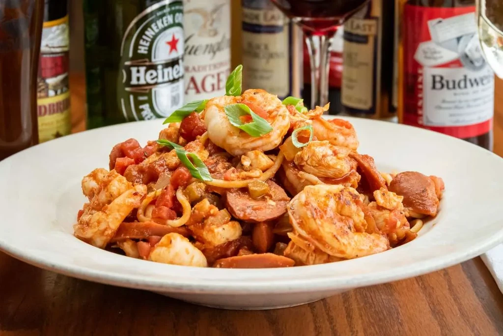 Shrimp, sausage, and pasta in red sauce, garnished with herbs.