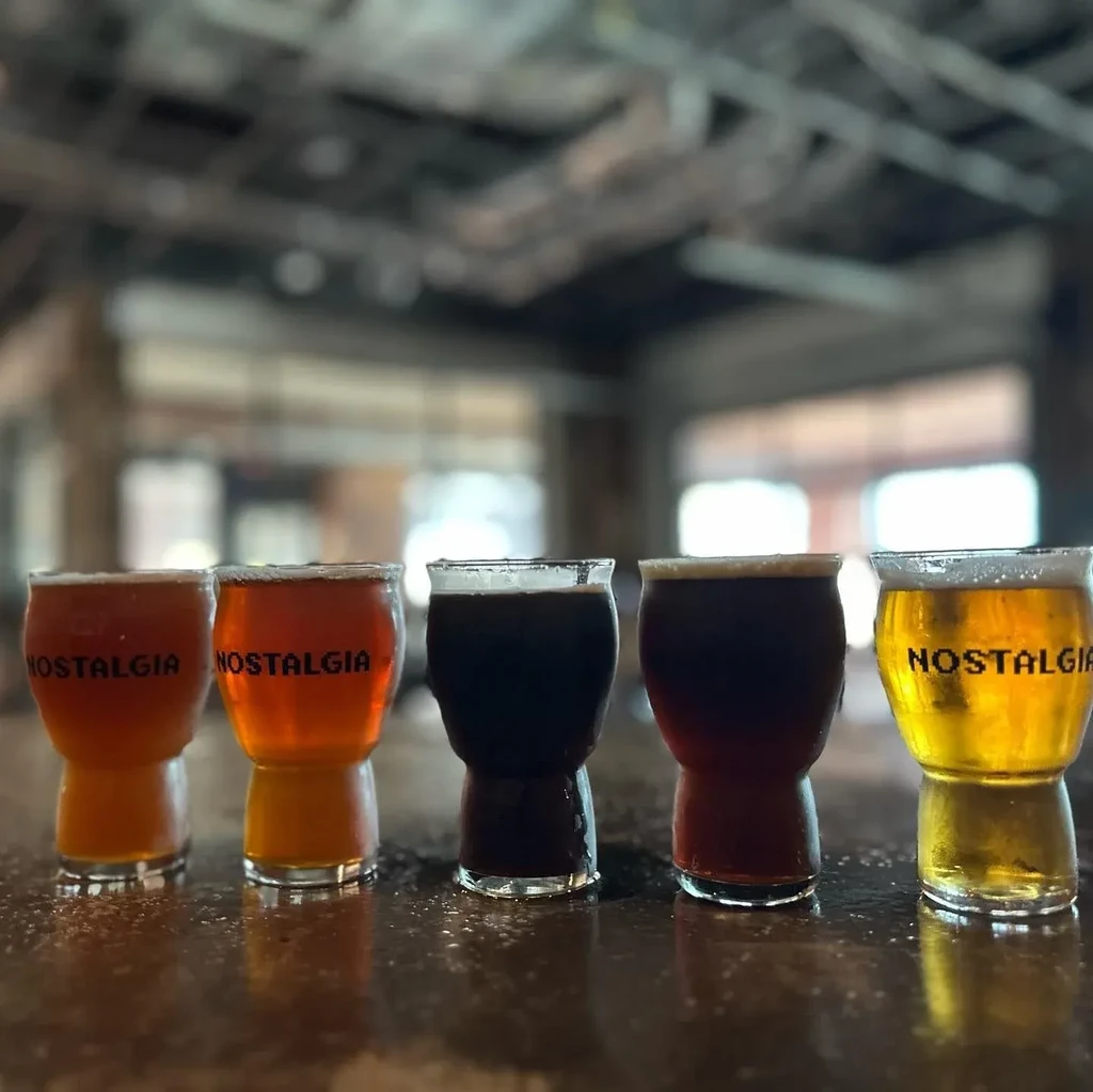 Five beer flight glasses, labeled NOSTALGIA, with various colored beers.