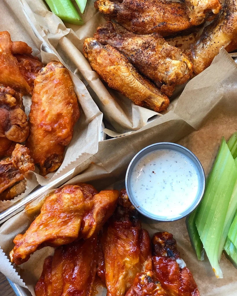 Top-down view of sauced and dry rub chicken wings with celery and dip.