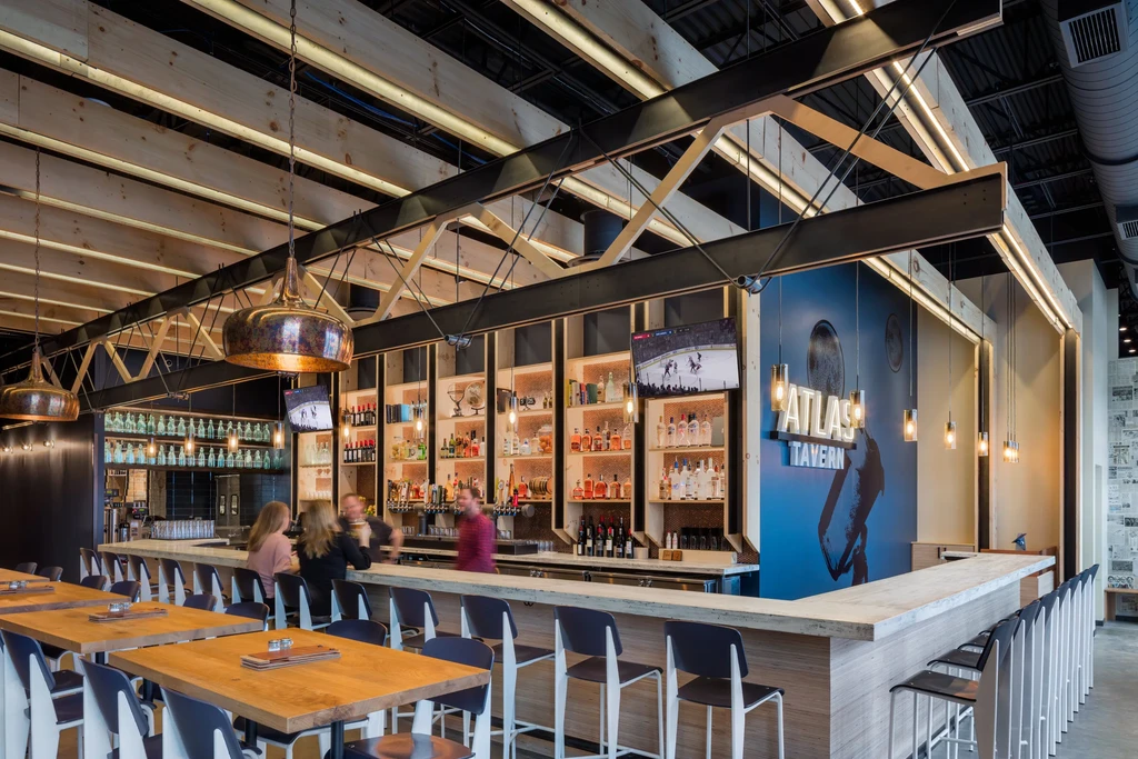 Modern Atlas Tavern bar featuring backlit liquor display and sports TVs.