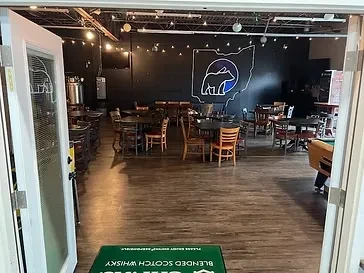Dimly lit bar interior with tables, Ohio mural, and a pool table.