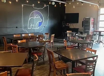 Casual restaurant interior with varied seating and a neon Ohio bear.