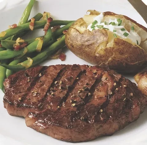 Grilled steak, green beans with bacon, and baked potato with chives.
