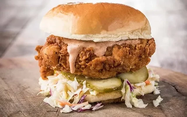 Crispy fried chicken sandwich with creamy sauce, pickles, and coleslaw.
