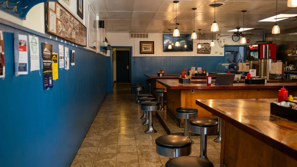 Empty casual restaurant bar with blue wall, flyers, and wooden counter.
