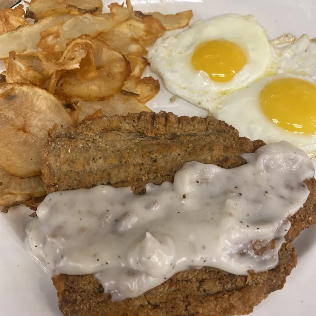 Country-fried steak and gravy with potatoes and two sunny-side-up eggs.