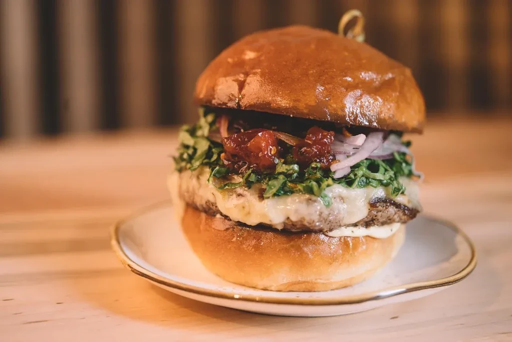 Gourmet beef burger with brioche bun, melted cheese, lettuce, and relish.