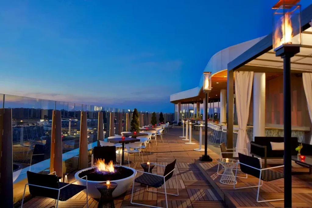 Expansive rooftop restaurant with city view, fire pit at dusk.