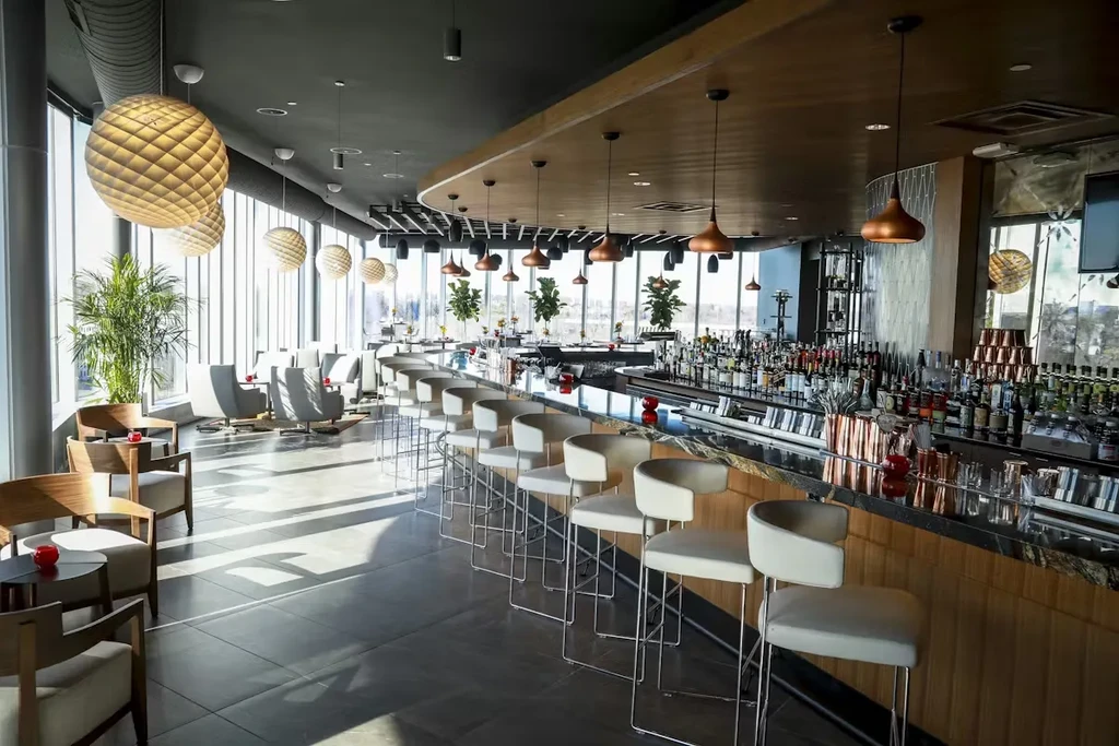Modern upscale bar interior with a long curving counter and lounge seating.