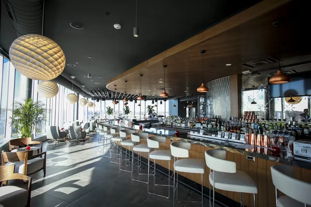 Modern bar and lounge with a stocked counter and large windows.