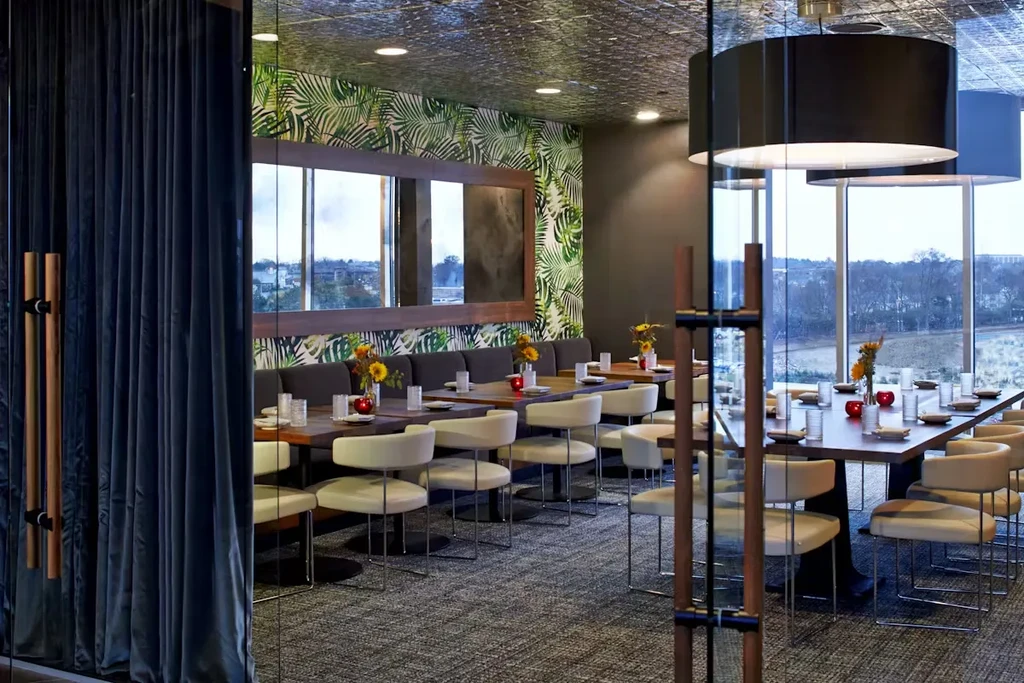 Empty modern restaurant with tropical wallpaper and scenic window view.