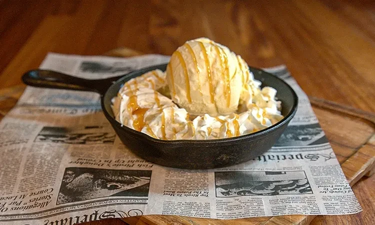 Cast-iron skillet with ice cream, whipped cream, and caramel.