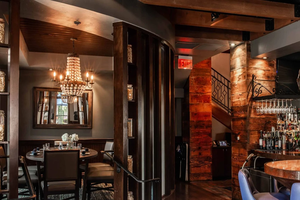 Warmly lit, stylish restaurant interior with dining and stocked bar.