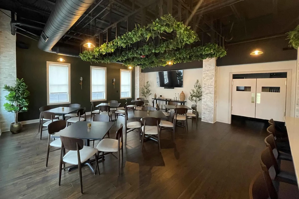 Modern restaurant dining room, green walls, suspended artificial greenery frame.