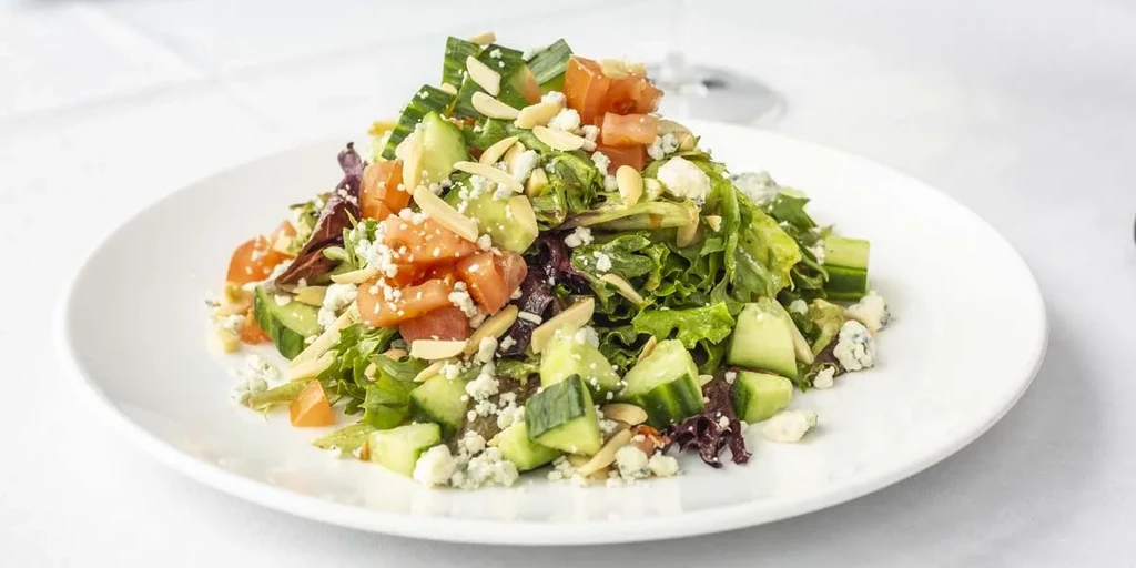 Fresh mixed green salad with tomatoes, cucumber, cheese, and almonds.