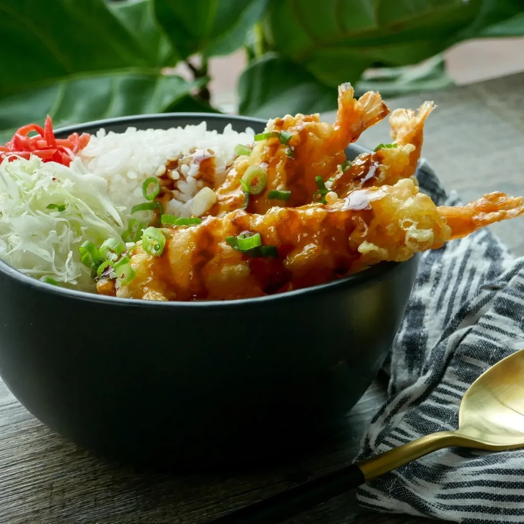 Close-up of tempura shrimp donburi with rice, cabbage, and pickled ginger.