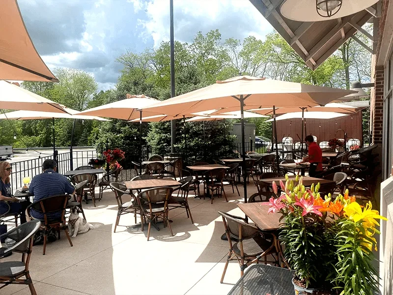 Vibrant outdoor dining patio with umbrellas, flowers, and scattered diners.