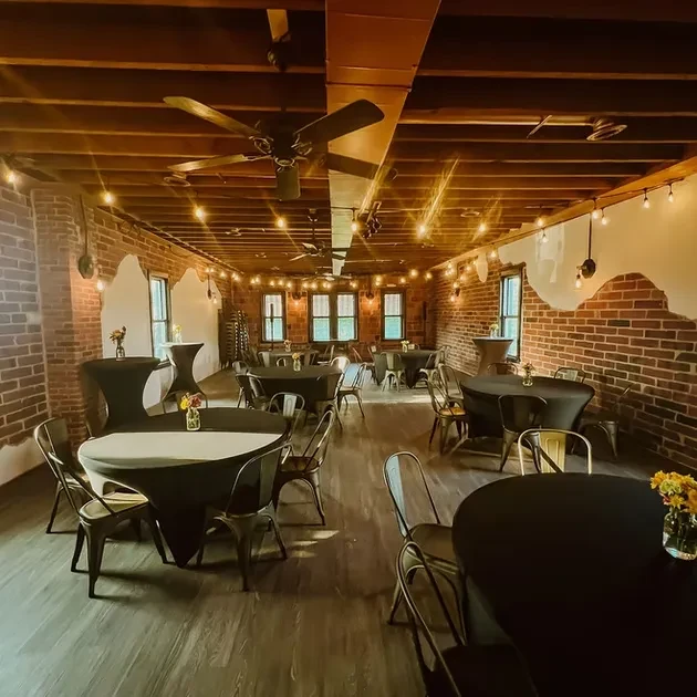 Empty dining room with exposed brick walls and wooden beams.