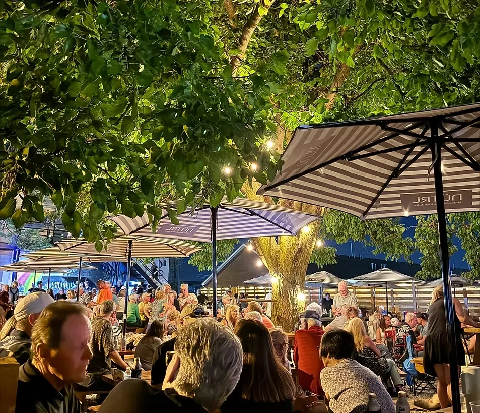 Lively outdoor patio at night with string lights and many guests.