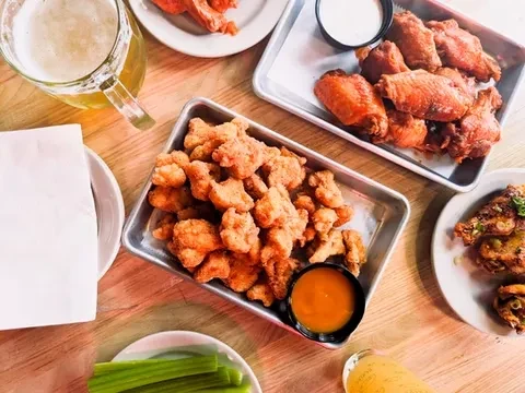 Overhead view: Fried chicken wings, bites, celery, and beer.