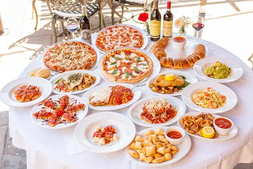 Vibrant spread of various Italian dishes and red wine outdoors.