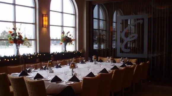 Elegantly set dining table in restaurant with snowy windows and festive decor.