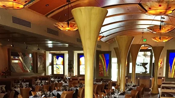 Upscale restaurant interior with fluted columns and colorful artistic lighting.