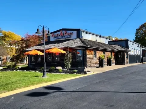 Rustic and modern Bros & Buns restaurant exterior with orange patio umbrellas.