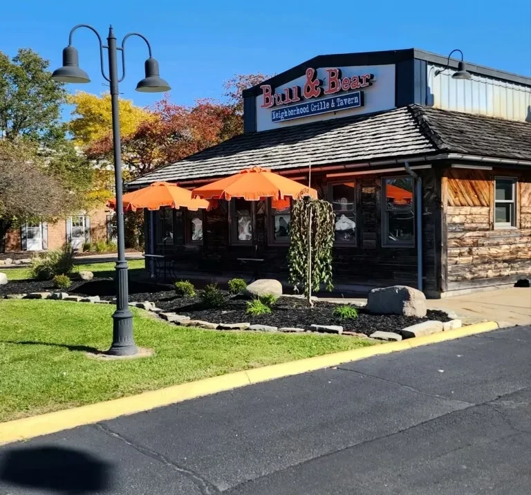 Rustic Bull & Bear restaurant exterior with orange umbrellas and autumn trees.