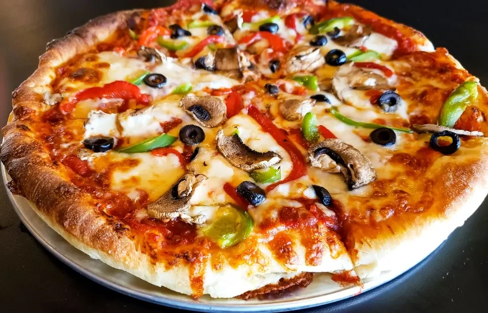 A large pizza with mozzarella, mushrooms, olives, and bell peppers.