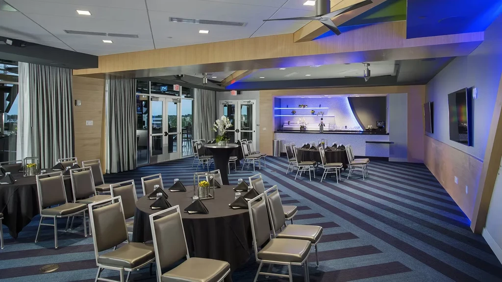 Modern event room with set tables, blue LED bar, and striped carpet.