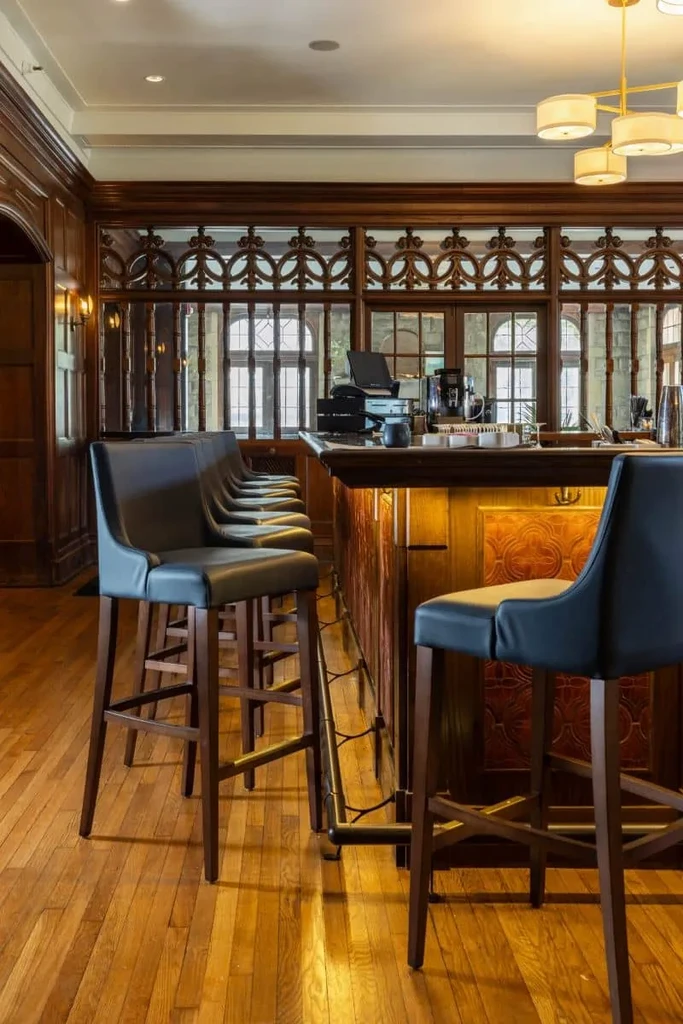 An empty dark wood bar counter and stools in an elegant lounge.