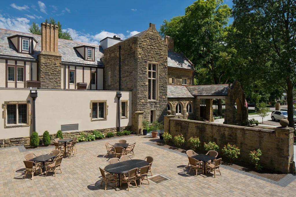 Grand stone building with an empty outdoor patio and dining sets.
