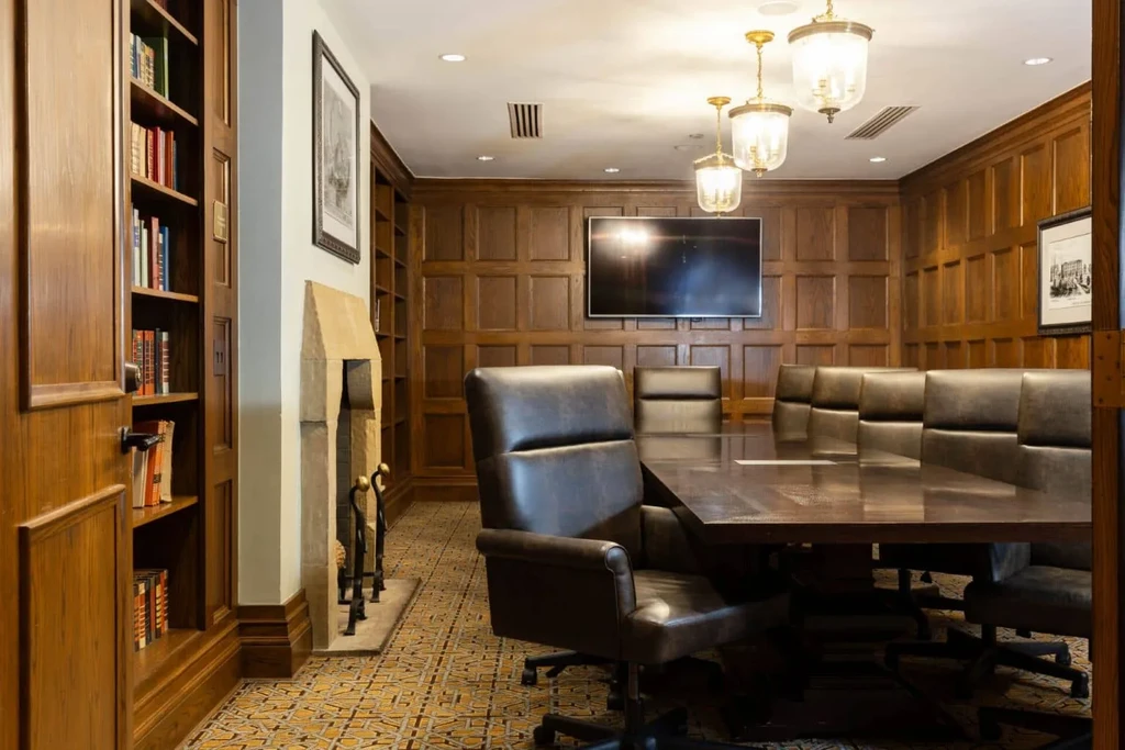 Wood-paneled private room with large table, executive chairs, and fireplace.