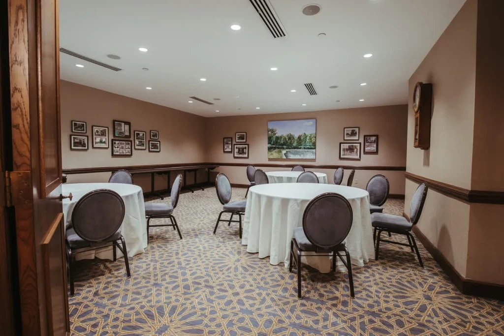 Set banquet room featuring round tables, upholstered chairs, and geometric carpet.