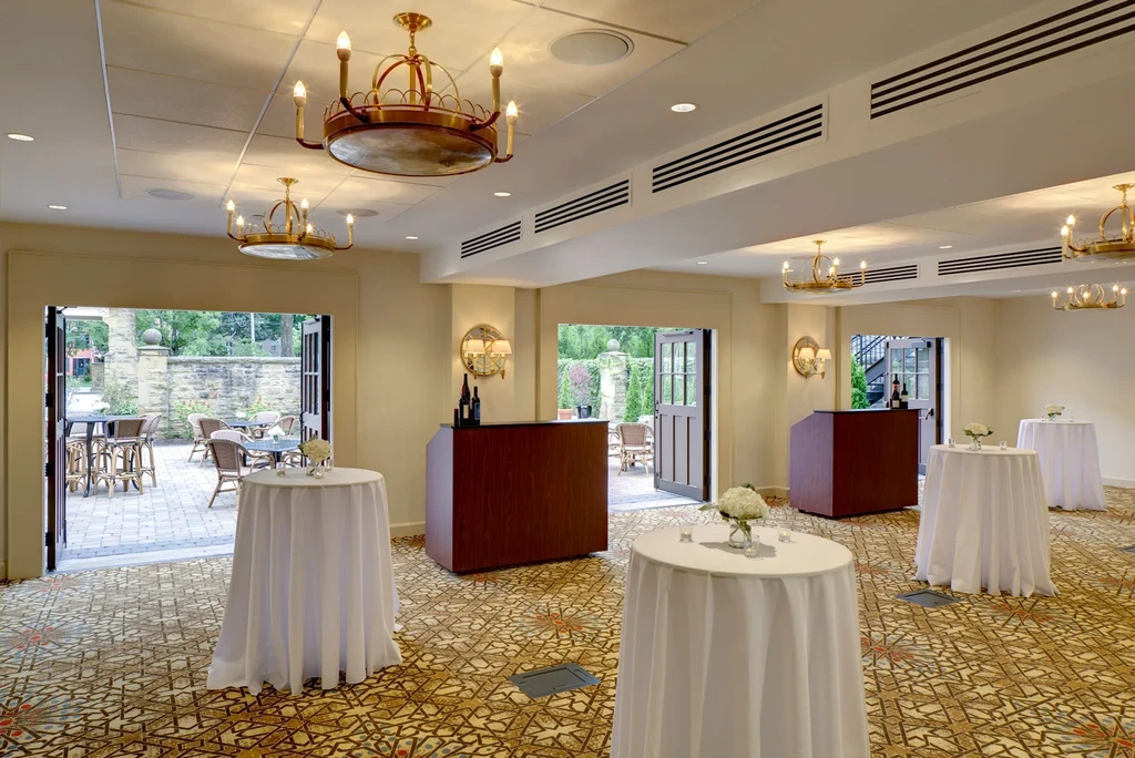 Elegant ballroom set for an event, outdoor patio in background.