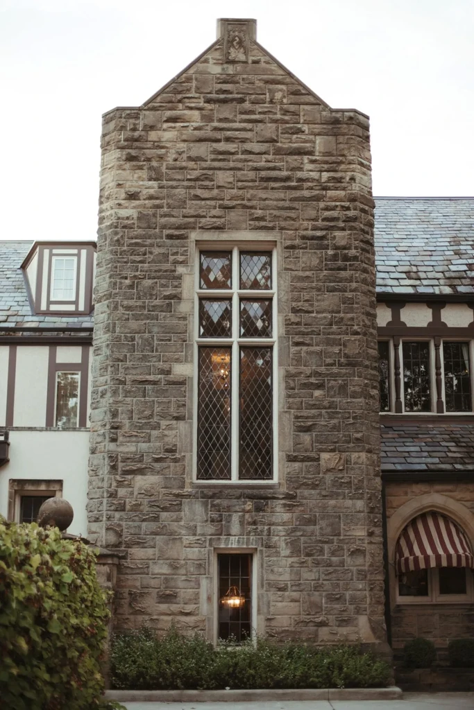 Grand multi-story stone building with gables, timber, and striped awning.