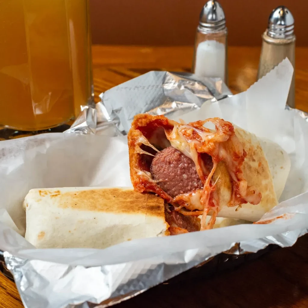 Large wrap cut open, showing meat, melted cheese, and sauce.