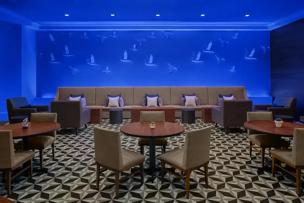 Modern lounge with blue bird mural, banquette seating, and geometric floor.