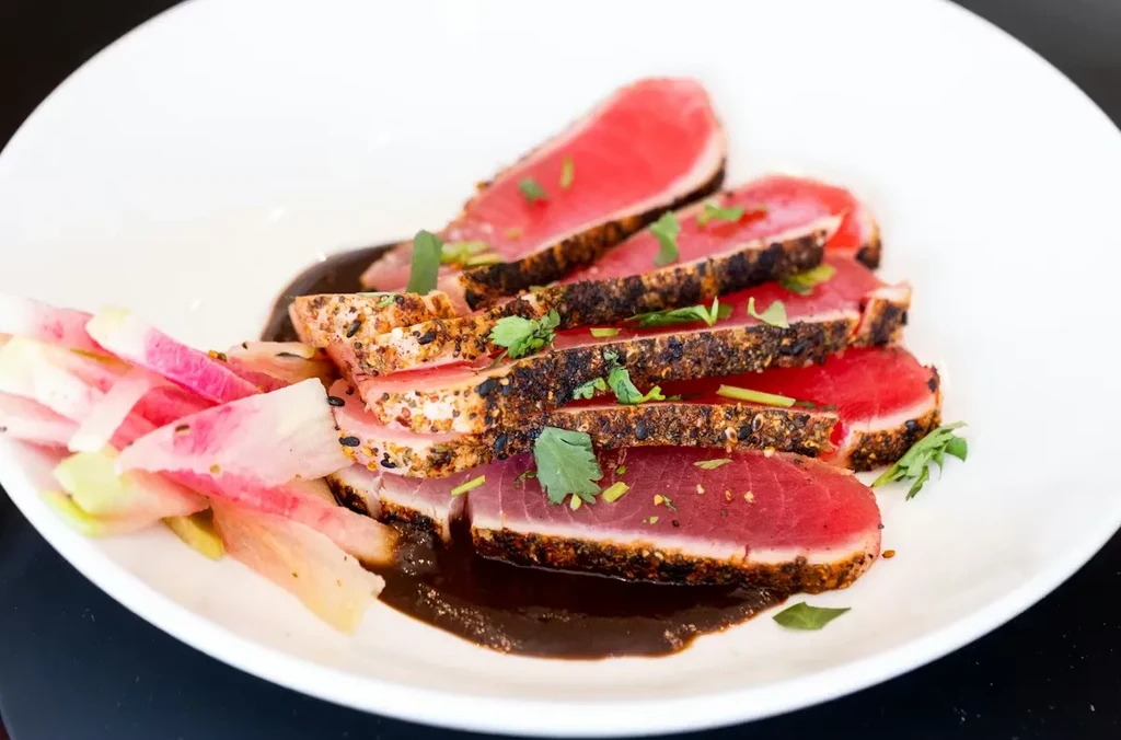 Thinly sliced rare seared tuna, sauce, herbs, and watermelon radishes.
