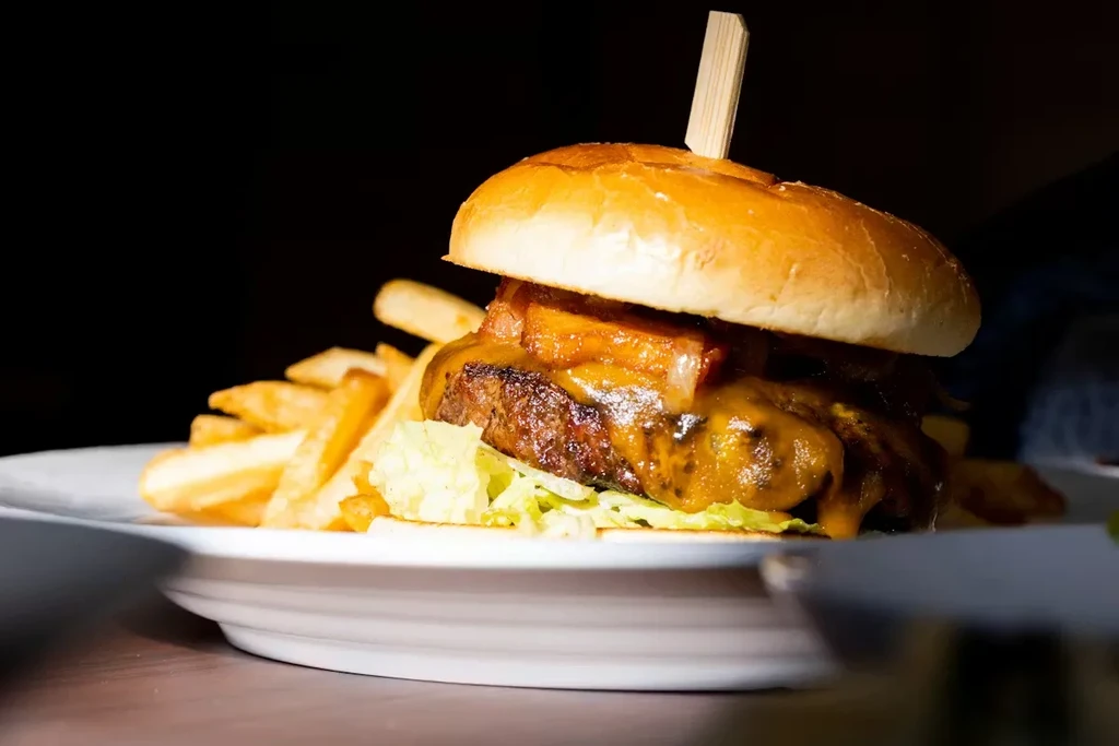 Beef burger with melted cheese, crispy bacon, lettuce, and golden fries.