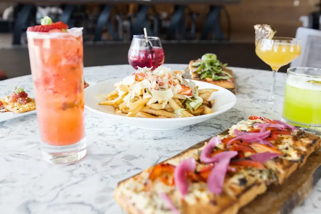 Artfully arranged gourmet dishes and colorful cocktails on a marble table.