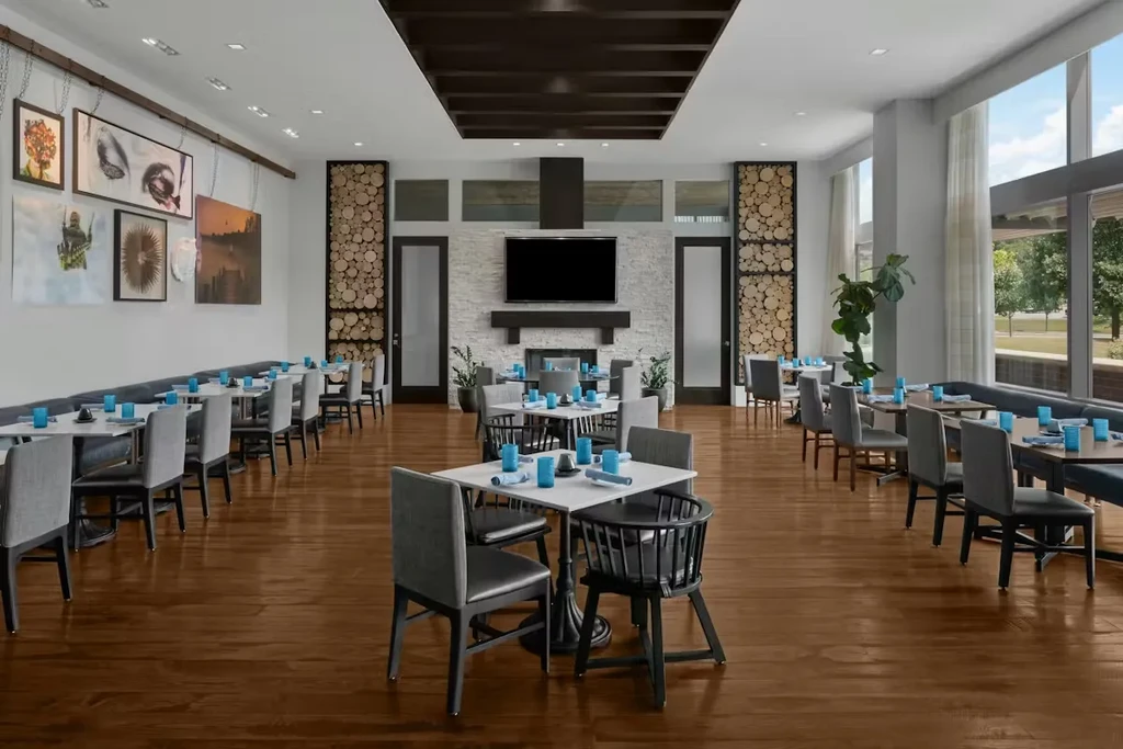 Modern restaurant dining area with tables, wall art, and fireplace.