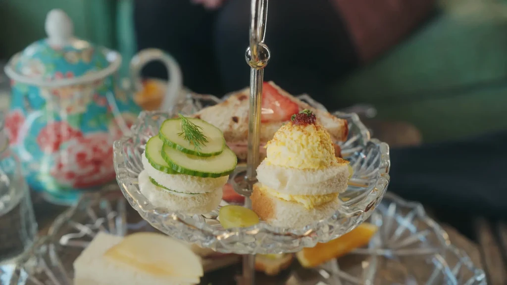 Tiered stand displaying cucumber, egg salad, and strawberry tea sandwiches.